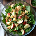 Freshly prepared Swiss Alpine Apple Salad in a glass bowl with apples, cheese, and herbs.
