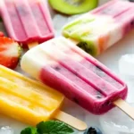 Homemade Fruit Popsicles arranged on summer-themed background