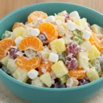 Colorful creamy fruit salad in a bowl with fresh fruit and dressing