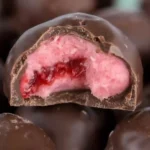 Close-up of chocolate-coated strawberry bon bons with creamy filling