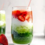 Layered iced strawberry matcha latte with glass straw
