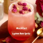 Lychee rose spritz mocktail in a gold-rimmed glass with rosebud garnish