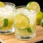Caipirinha cocktail recipe in glass with lime and ice on wooden tray
