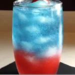 Patriotic slushy mocktail with red, white, and blue layers in a tall glass